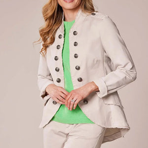 Woman wearing a light-colored jacket with button details on a plain background