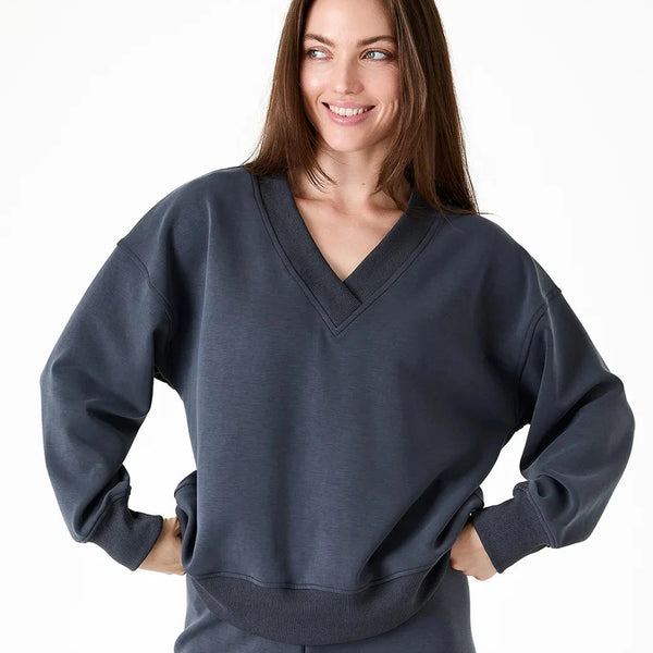 A woman modeling a dark slate gray V-neck sweatshirt and matching sweatpants against a plain white background.
